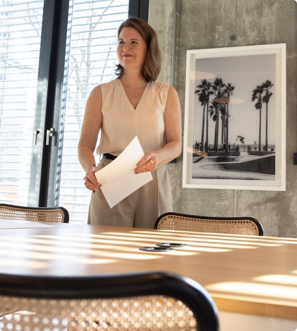 Julia Späth steht in einem Konferenzraum mit Papieren in der Hand, bereit für eine Präsentation.